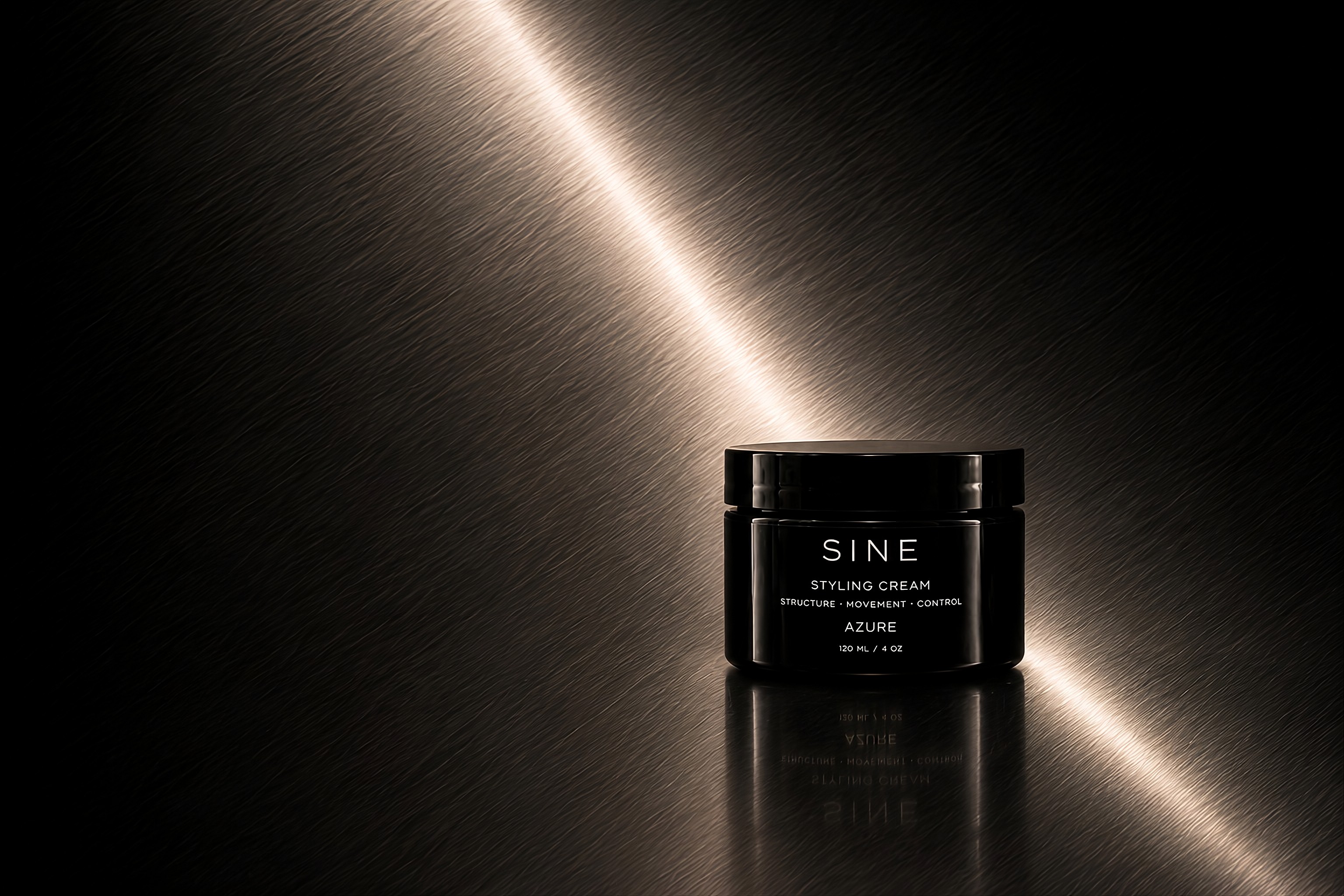 Black jar of Azure styling cream on a brushed-metal surface with a dramatic diagonal light streak