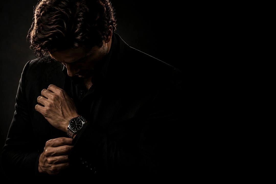 Man in a black suit adjusting his watch cuff